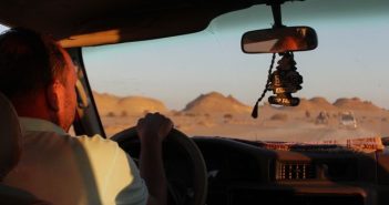 man driving car in desert
