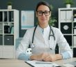 pretty femal doctor sitting at her desk wearing glasses
