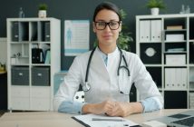 pretty femal doctor sitting at her desk wearing glasses